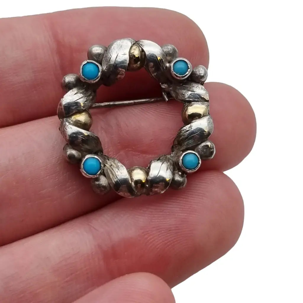 Broche antiguo redondo años 50 de plata y oro con bolas azul turquesa.