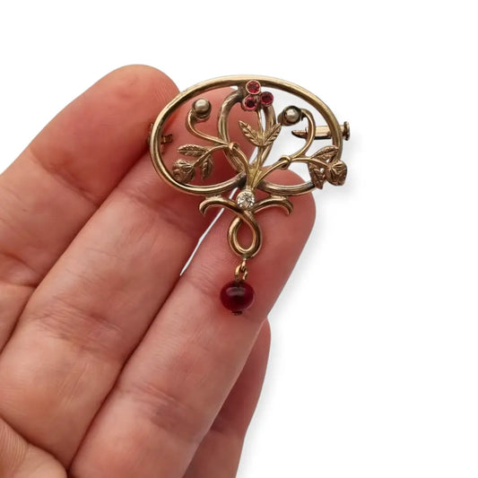 Broche Art Nouveau dorado con flor calada perlas y granates Circa 1900.