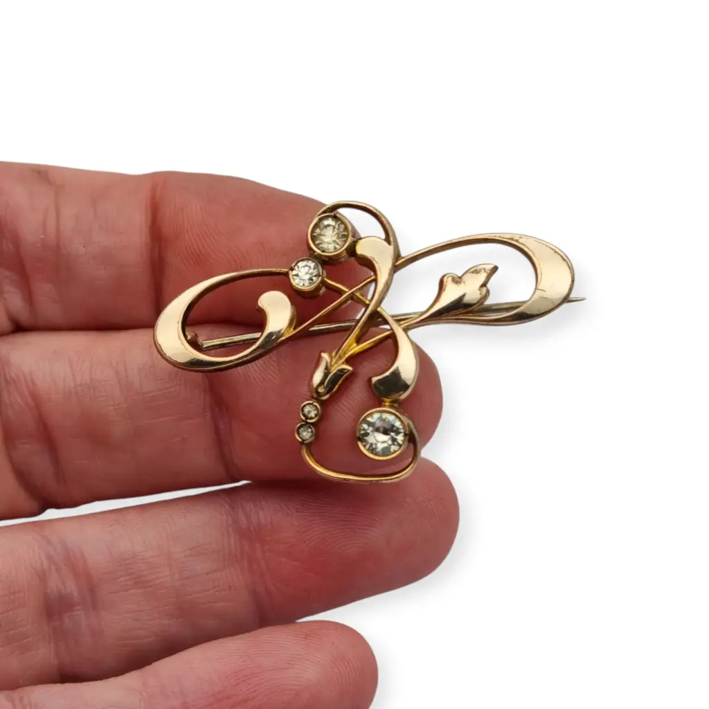 Broche Belle Époque de metal dorado con cristales y diseño floral curvilíneo