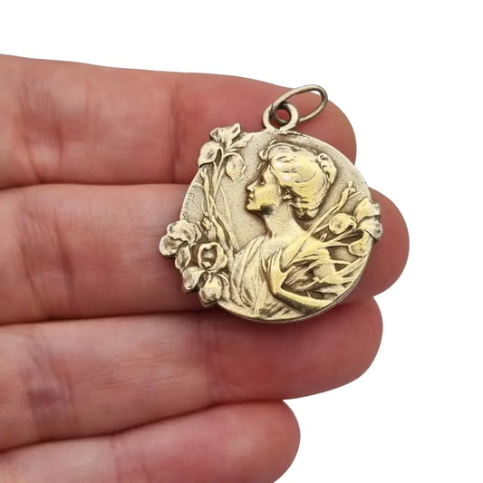 Medalla colgante Art Nouveau en plata dorada con mujer entre lirios firmada E.