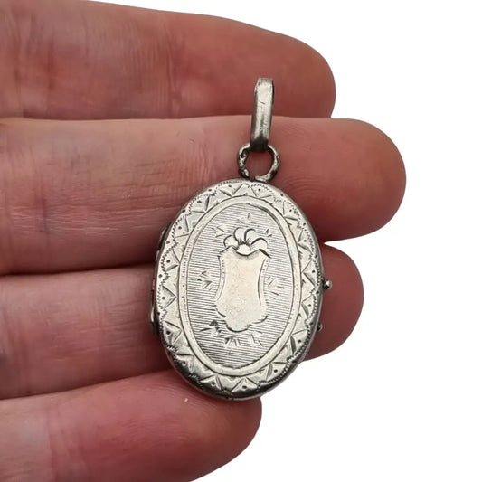 Medallón guardapelo ovalado floral de plata antigua grabada con escudo.