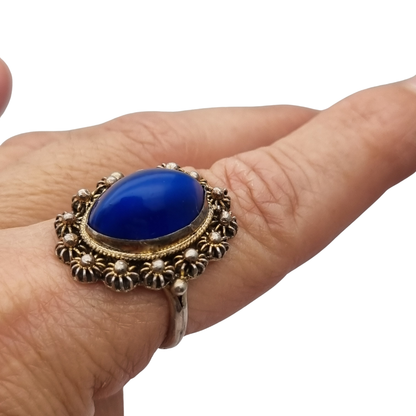 Mid-Century silver ring with blue cabochon and highly ornate floral frame, 1960