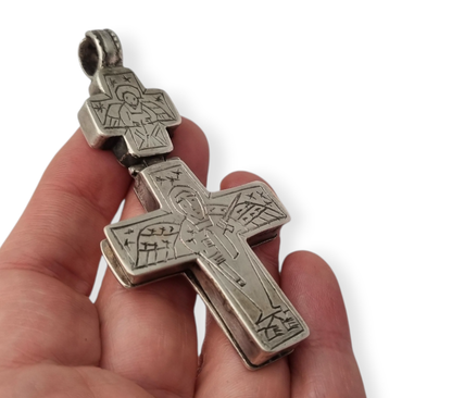 Antique Byzantine-style silver reliquary cross with engraved religious scenes.
