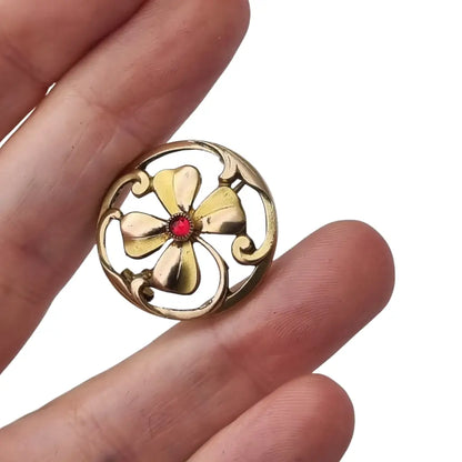 Broche antiguo Art Nouveau en metal dorado flor calada con cristal rojo central