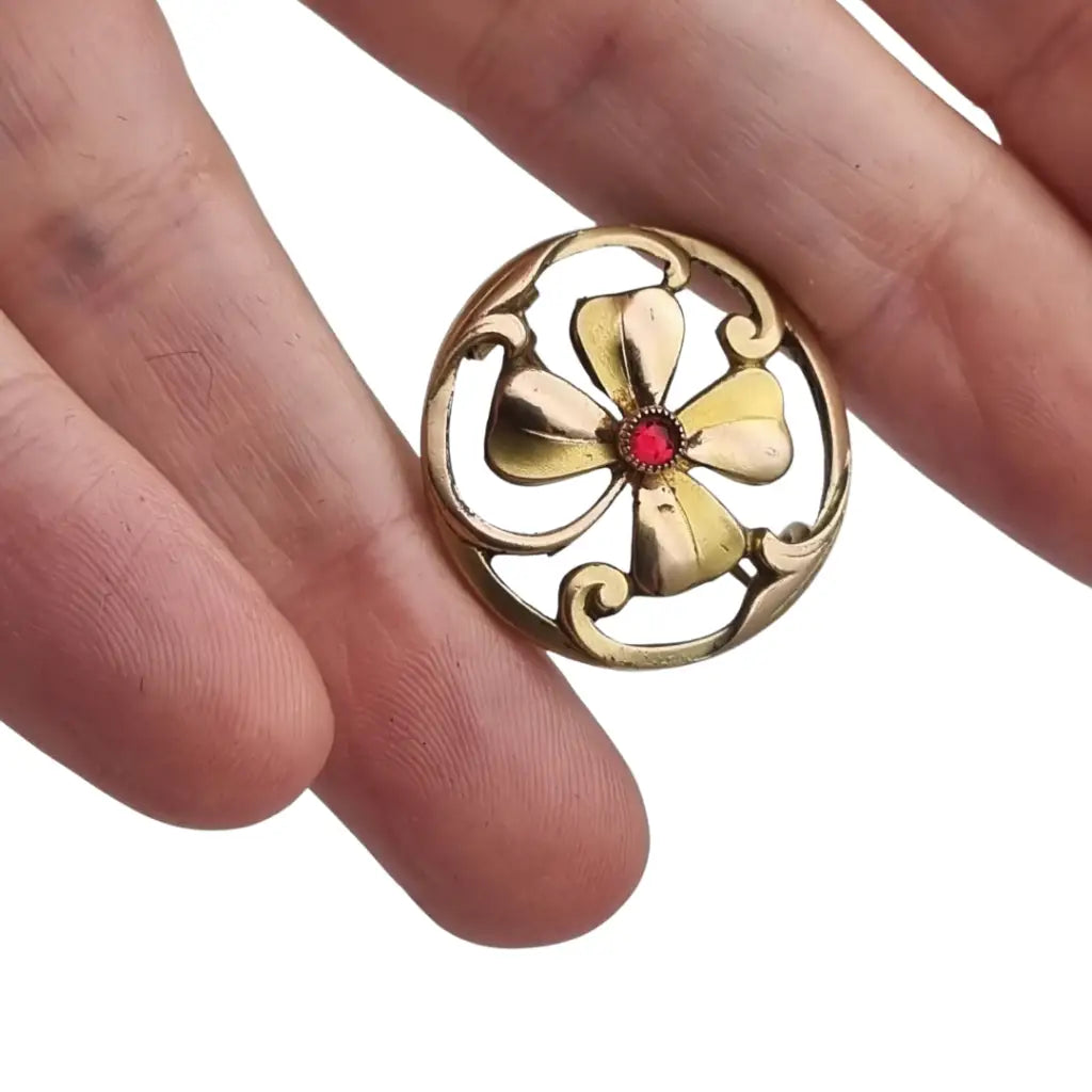 Broche antiguo Art Nouveau en metal dorado flor calada con cristal rojo central