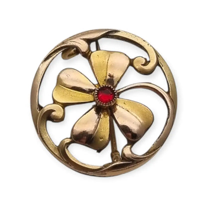 Broche antiguo Art Nouveau en metal dorado flor calada con cristal rojo central