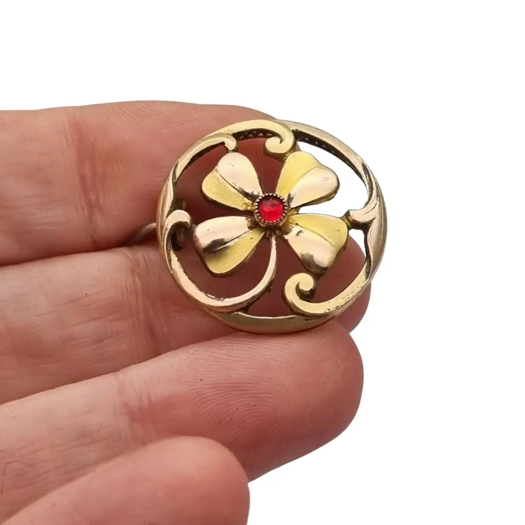 Broche antiguo Art Nouveau en metal dorado flor calada con cristal rojo central