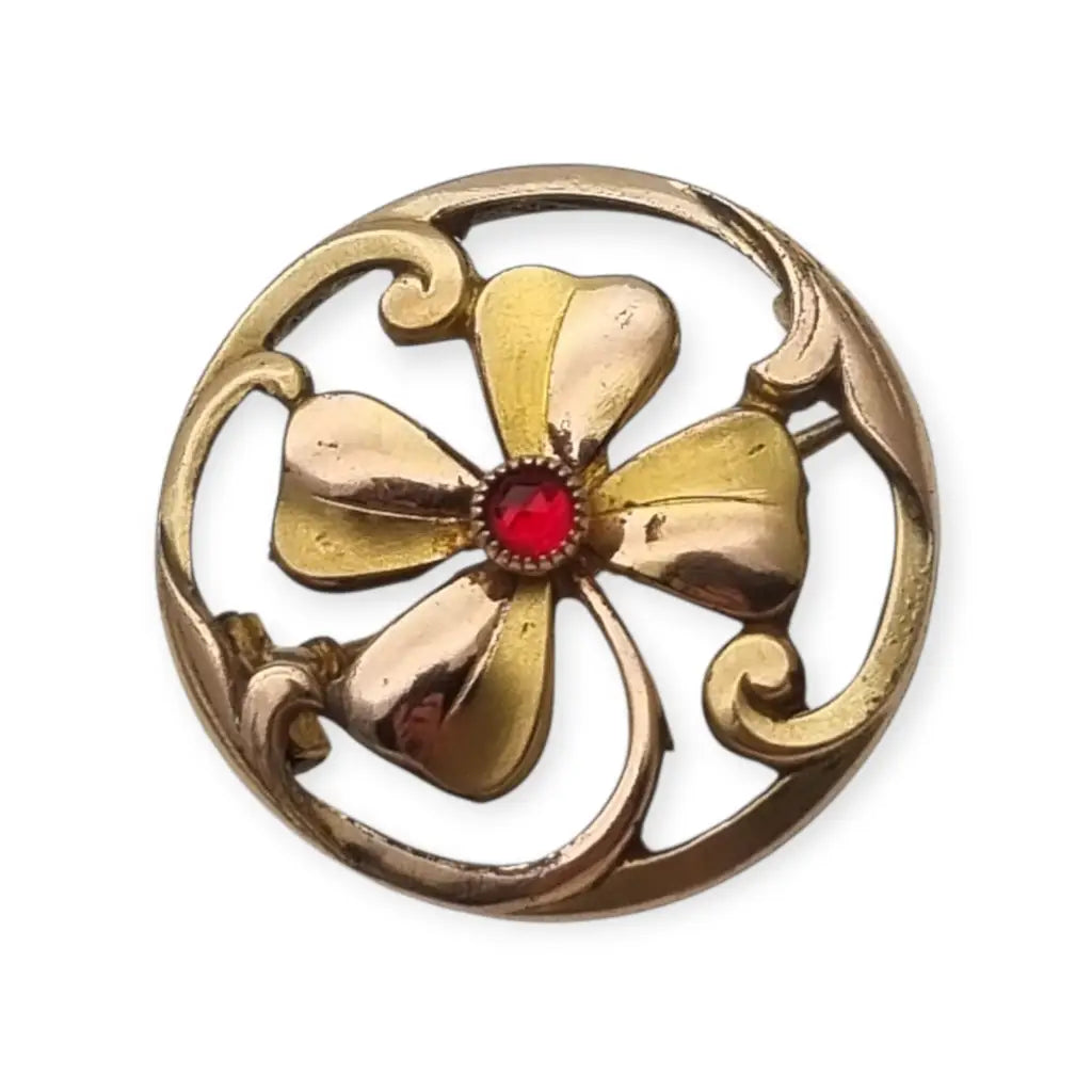 Broche antiguo Art Nouveau en metal dorado flor calada con cristal rojo central