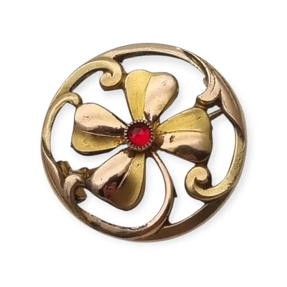 Broche antiguo Art Nouveau en metal dorado flor calada con cristal rojo central