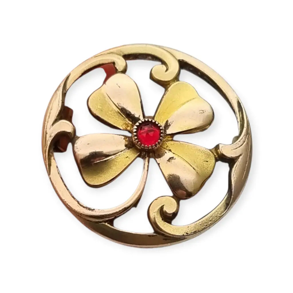 Broche antiguo Art Nouveau en metal dorado flor calada con cristal rojo central