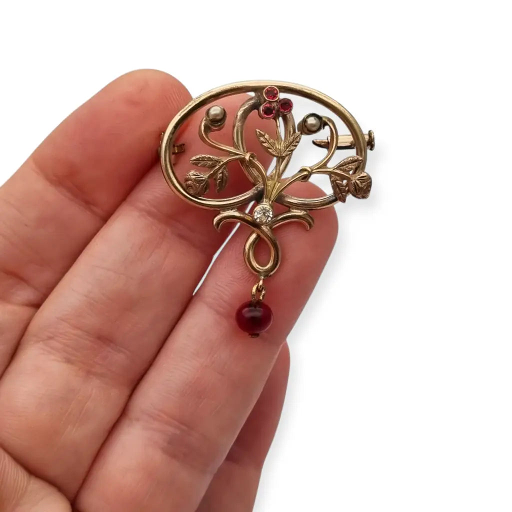 Broche Art Nouveau dorado con flor calada perlas y granates Circa 1900.