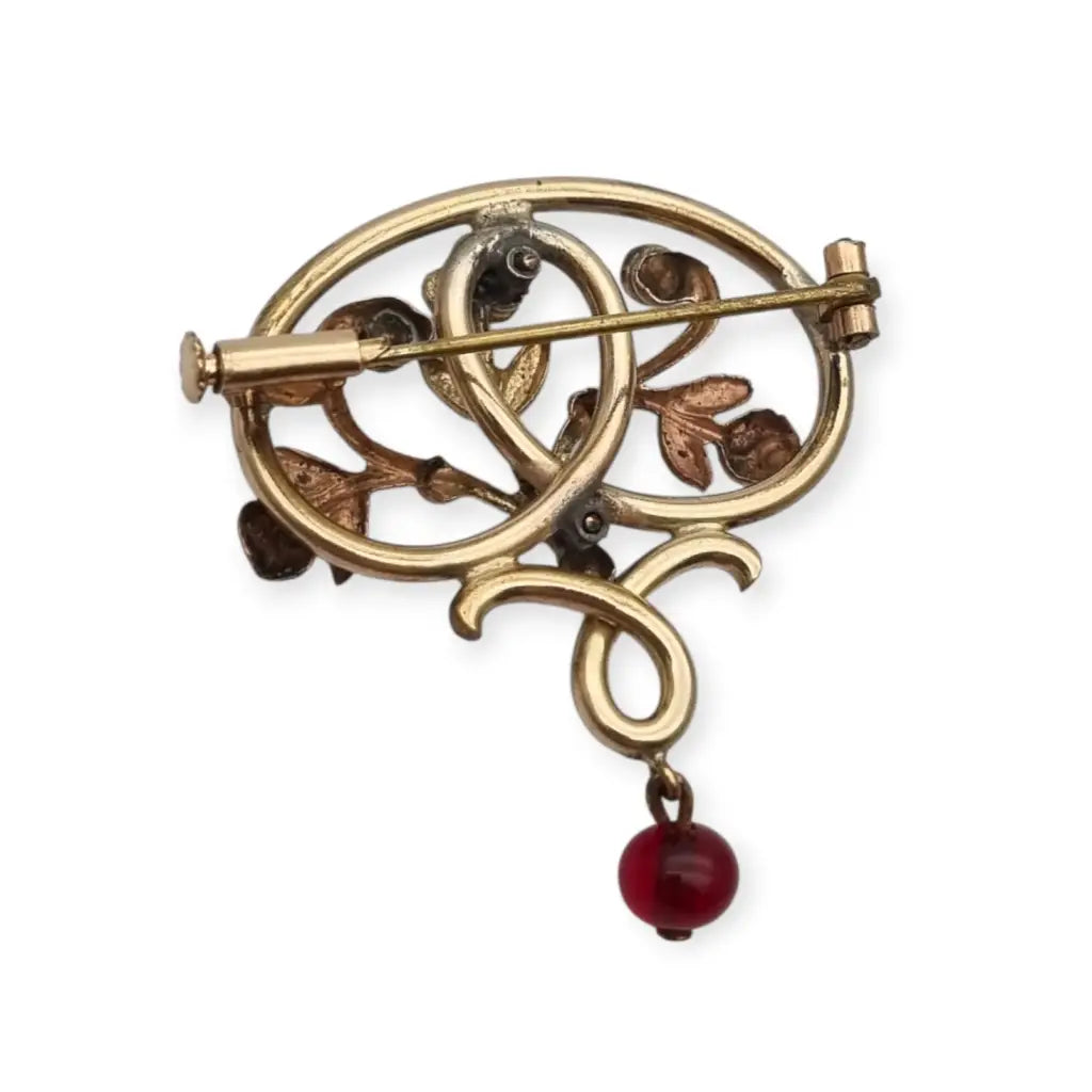 Broche Art Nouveau dorado con flor calada perlas y granates Circa 1900.