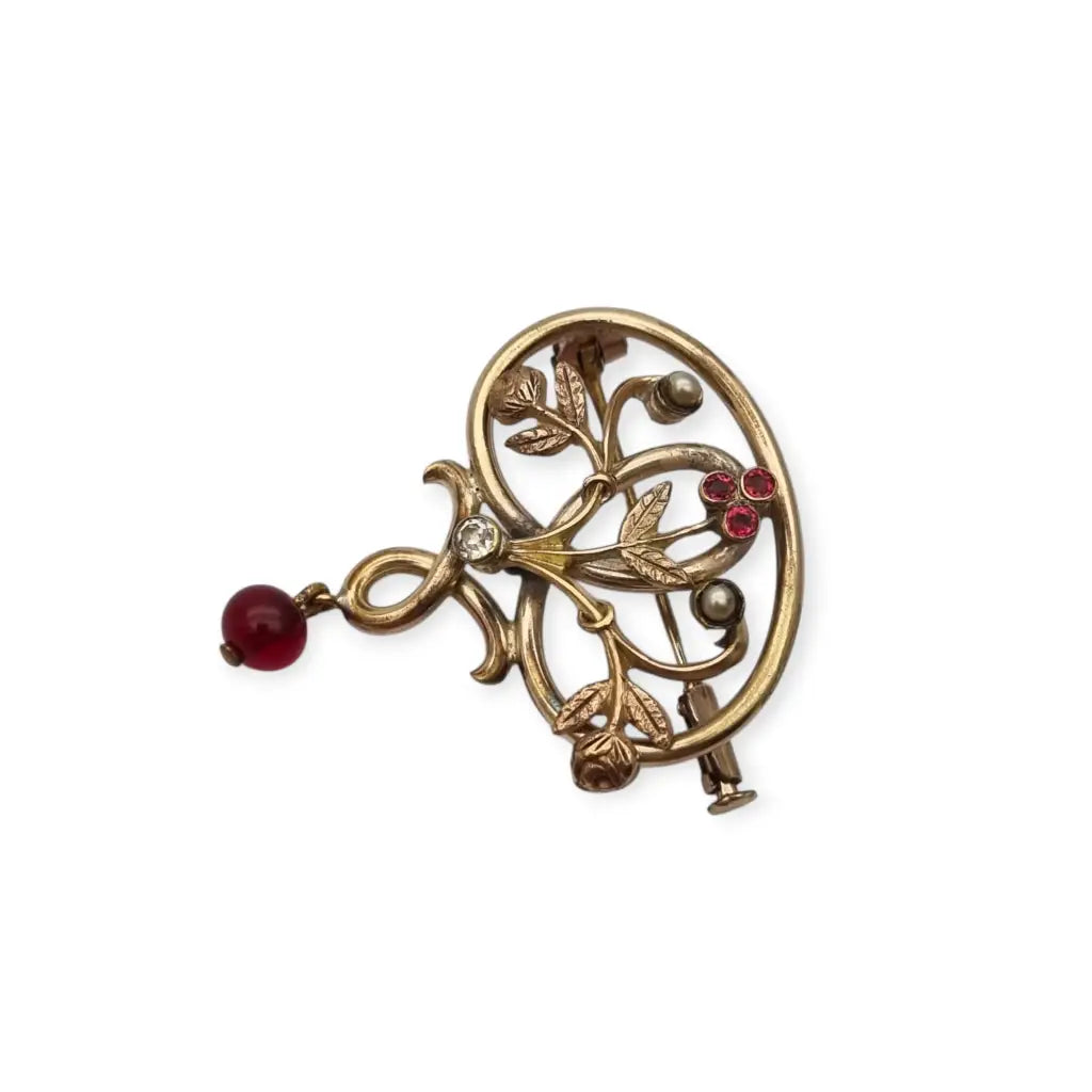 Broche Art Nouveau dorado con flor calada perlas y granates Circa 1900.