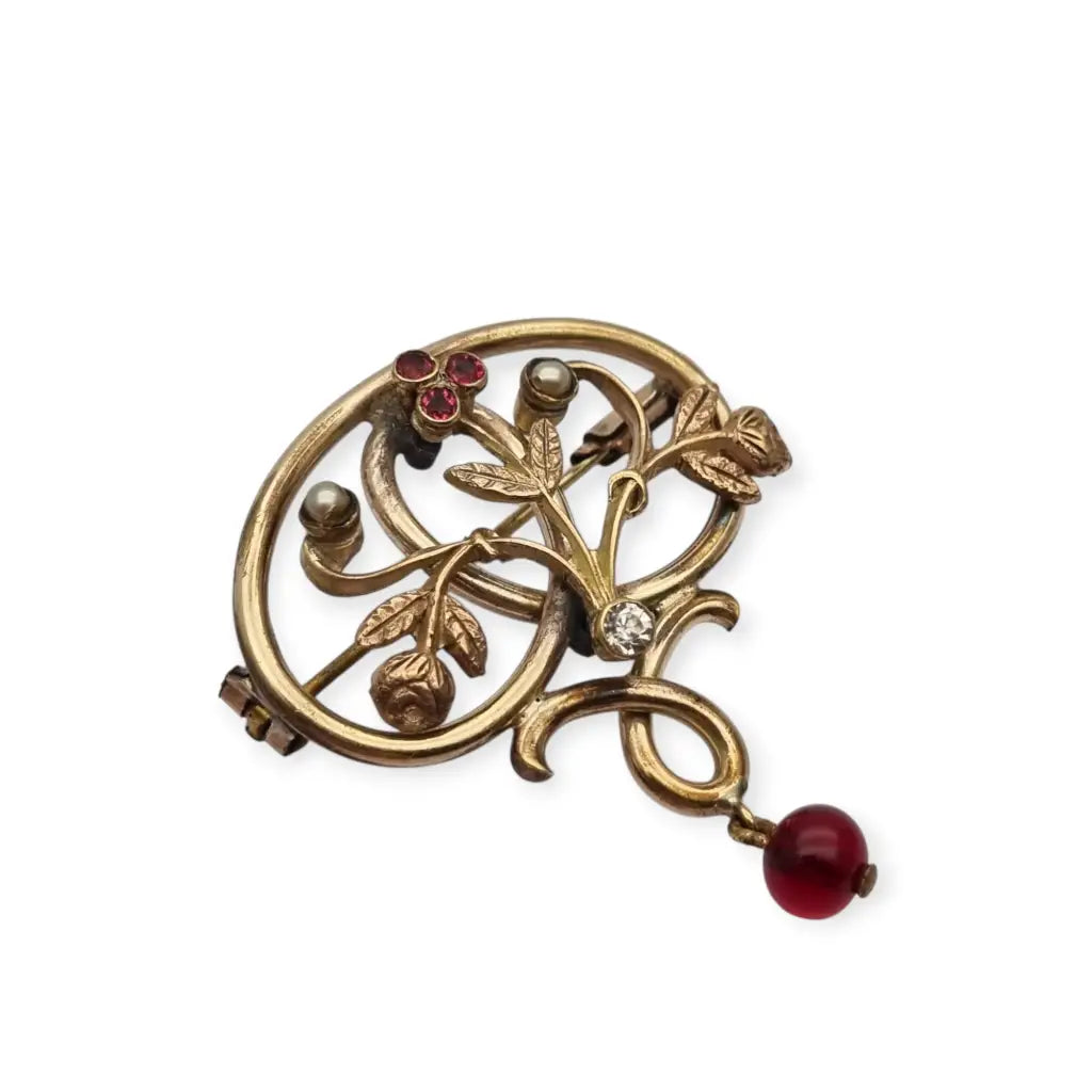 Broche Art Nouveau dorado con flor calada perlas y granates Circa 1900.