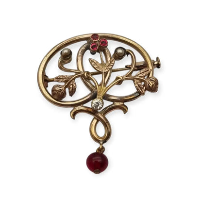 Broche Art Nouveau dorado con flor calada perlas y granates Circa 1900.