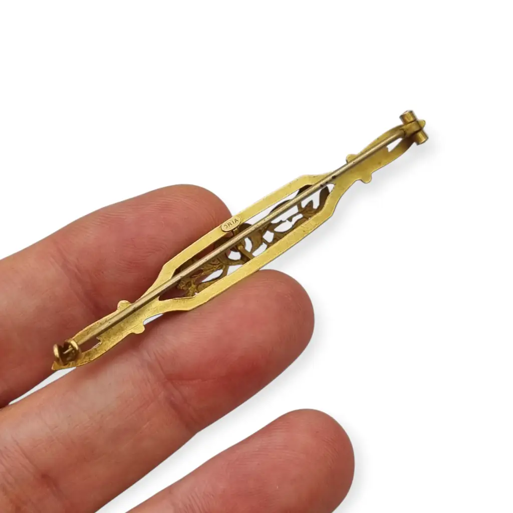 Broche Art Nouveau de Oria en oro laminado con flor calada y cristal rojo Circa