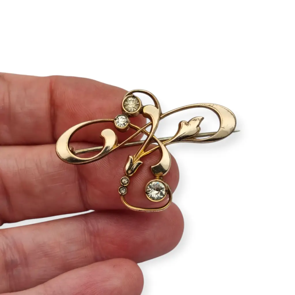 Broche Belle Époque de metal dorado con cristales y diseño floral curvilíneo