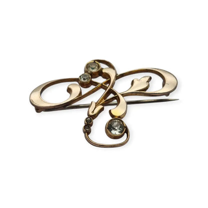 Broche Belle Époque de metal dorado con cristales y diseño floral curvilíneo