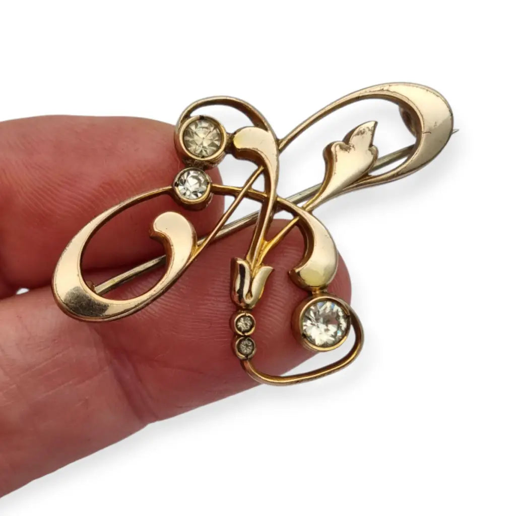 Broche Belle Époque de metal dorado con cristales y diseño floral curvilíneo