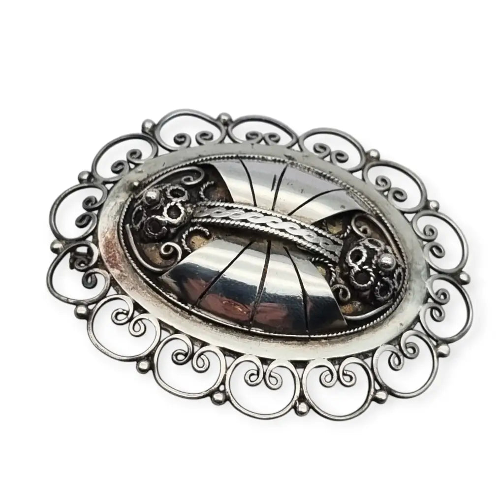 Broche ovalado de plata con filigrana popular detallada y diseño Art Nouveau.