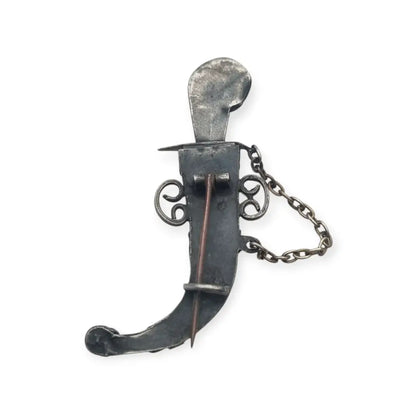 Broche de plata en forma daga con detalles dorados y pedrería colores