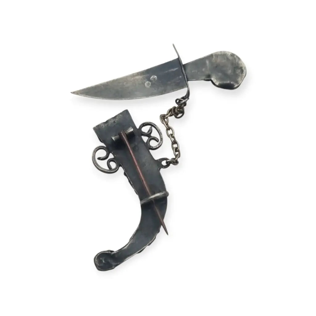 Broche de plata en forma daga con detalles dorados y pedrería colores