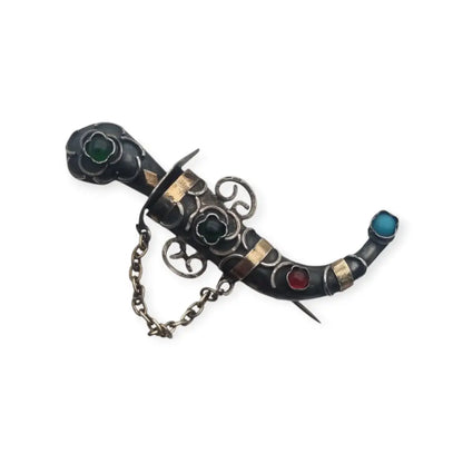 Broche de plata en forma daga con detalles dorados y pedrería colores