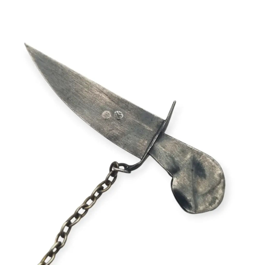 Broche de plata en forma daga con detalles dorados y pedrería colores