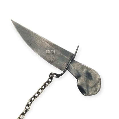 Broche de plata en forma daga con detalles dorados y pedrería colores