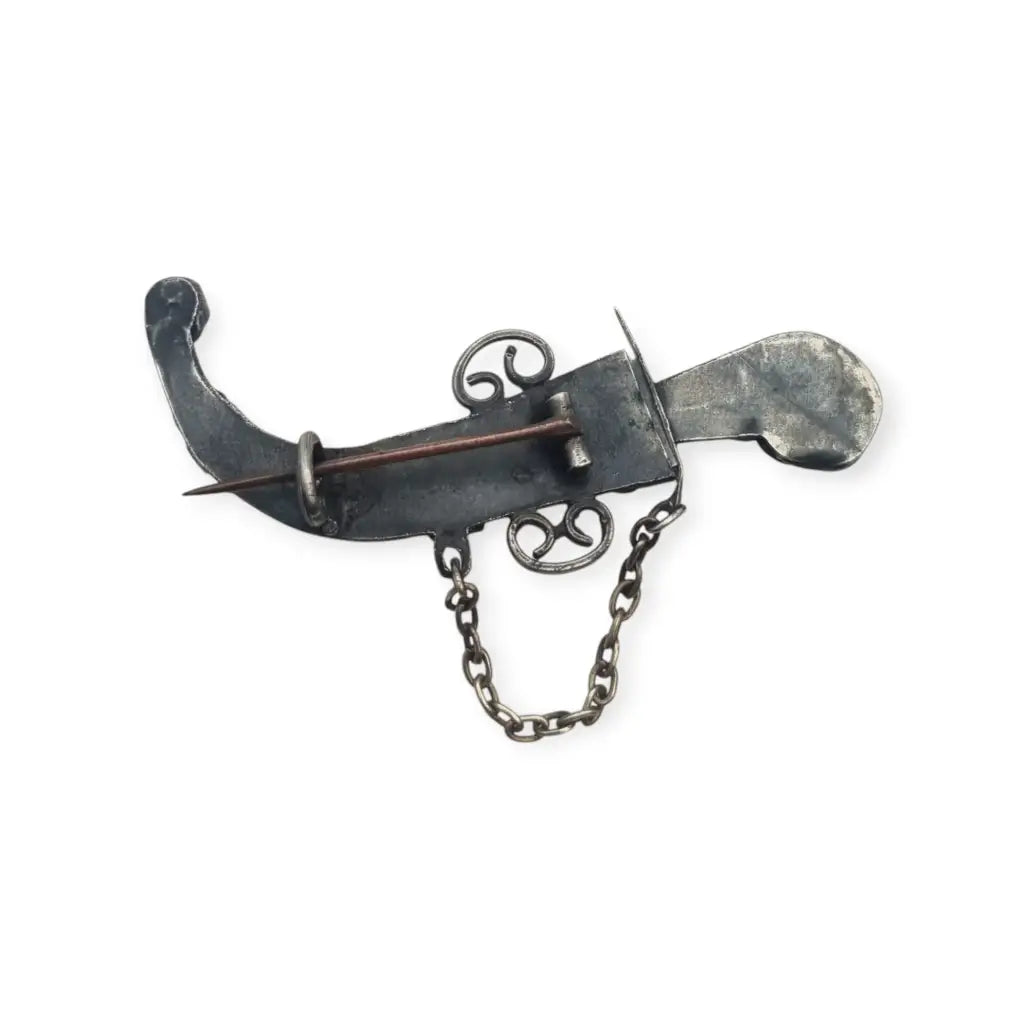 Broche de plata en forma daga con detalles dorados y pedrería colores