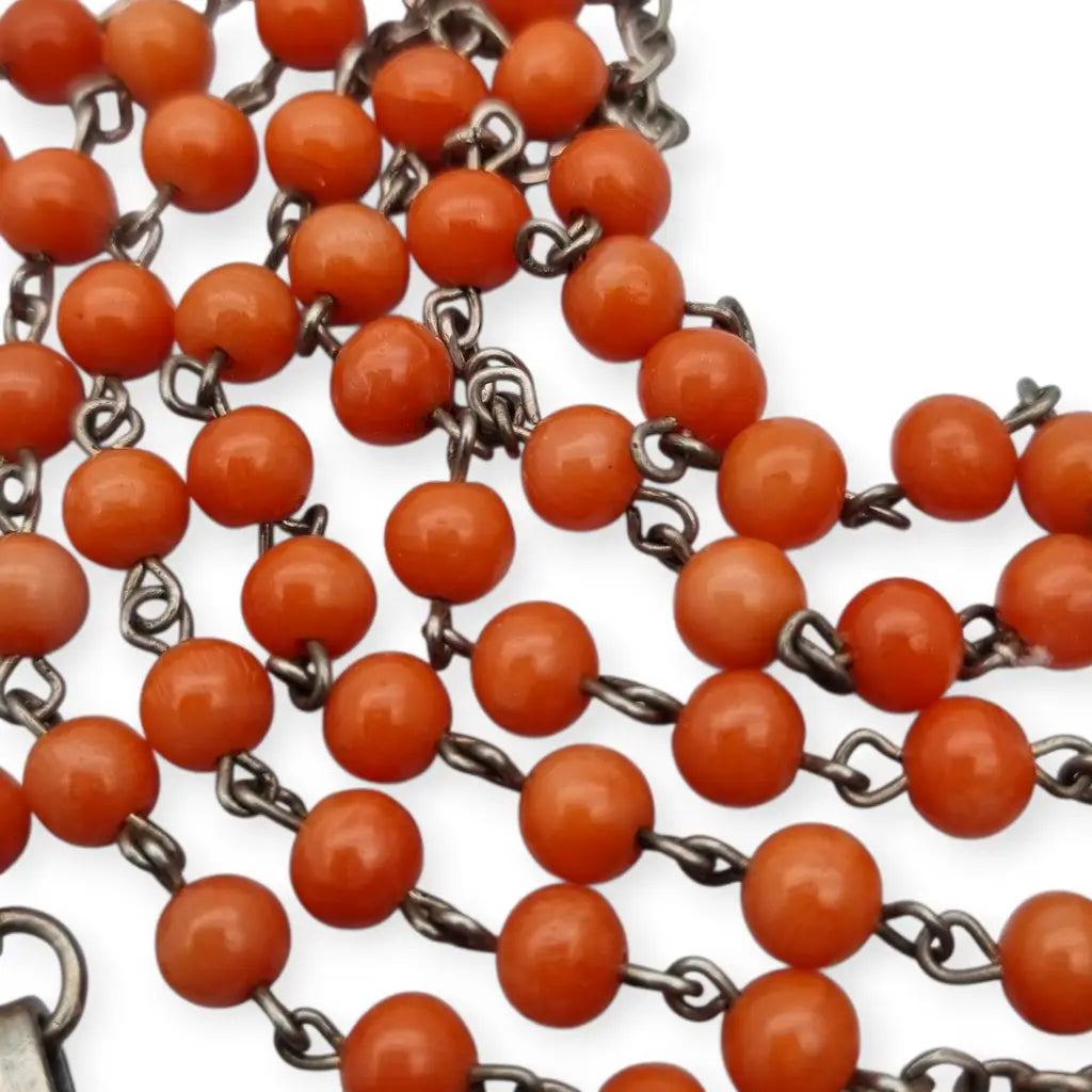 Rosario en plata con cuentas de coral rojo cruz estilizada artesanal estilo